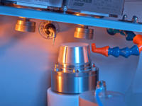 Laboratory testing machine with a metallic cylindrical sample holder under inspection tools.