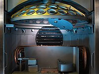 Interior of industrial machine with circular component and multiple openings above mechanical parts