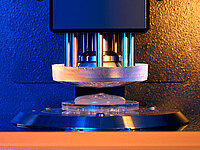 Machine precisely pressing a glass lens into a holder during the manufacturing process.