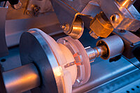 Machine grinding or precisely processing a glass lens during the manufacturing process.