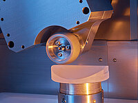 Close-up of a laboratory cutting machine with a rotating wheel tool shaping a sample