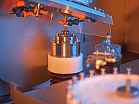 Close-up of a Satisloh SPM-10 grinding machine processing micro lenses in precision optics manufacturing.