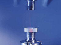 Laser beam directed onto a cylindrical sample in a laboratory testing setup