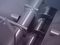 Close-up of a metallic screw conveyor mechanism inside industrial machinery.