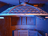 Interior of semiconductor processing equipment showing a circular wafer holder with multiple slots.