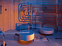 nterior view of industrial semiconductor equipment with metal pipes and round processing chambers.