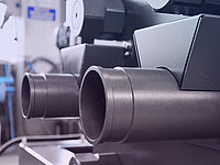 Close-up of industrial machine pipes and cylindrical components in a laboratory setting.