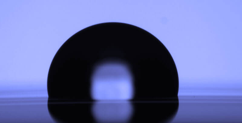 Upright semiconductor wafer shown in silhouette with blue backlighting.