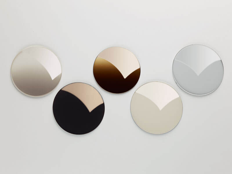 Five semiconductor wafers in different reflective shades, arranged on a light background.