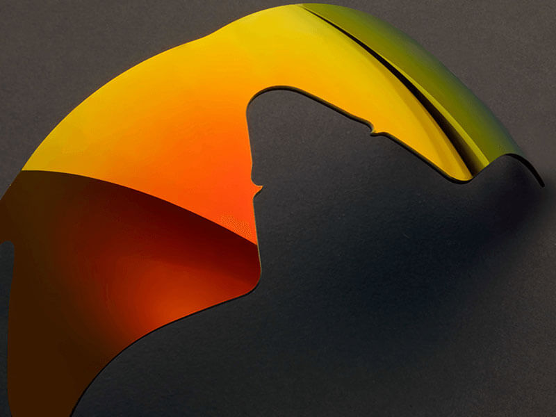 Bent semiconductor wafer with reflective orange and green surface on a dark background.