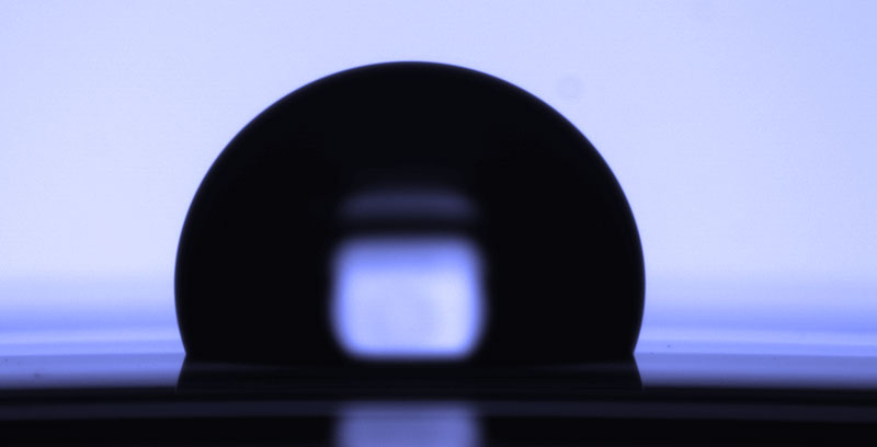 Dark silhouette of a semiconductor wafer against a blue backlit background.