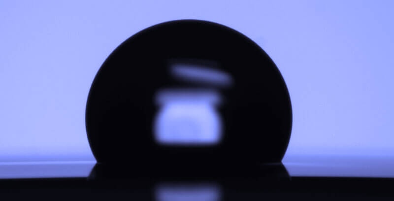 Silhouette of a semiconductor wafer standing upright against a blue illuminated background.