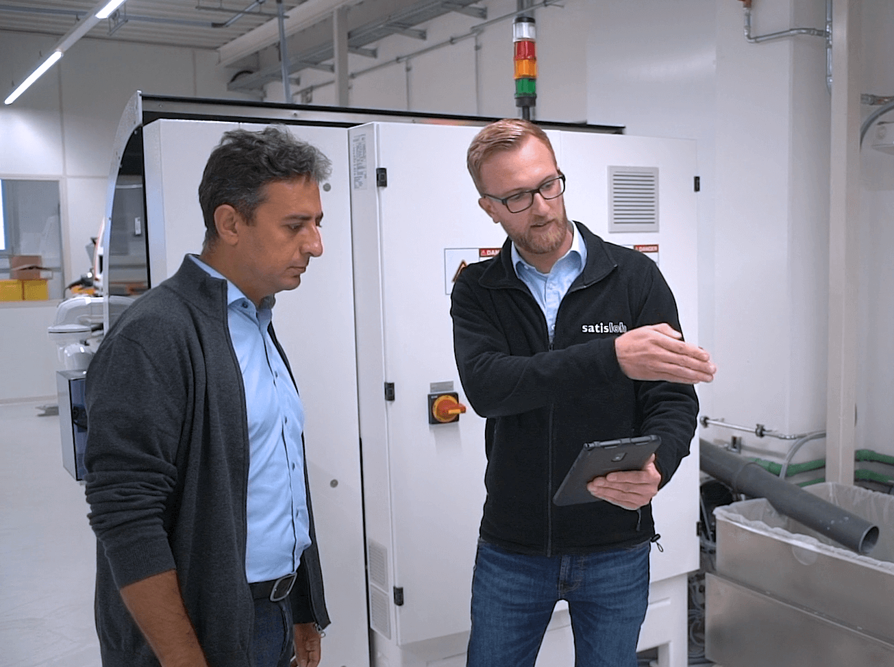 A man in a lab showing and consulting an other man the system of the lab.