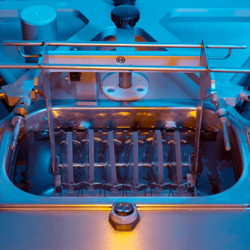 Close-up of industrial machine chamber with metal rods and liquid container