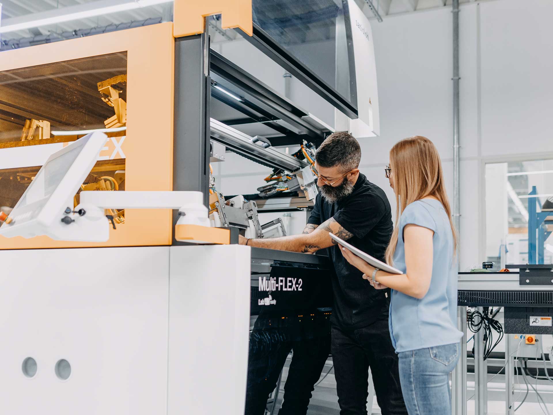Group of people operating and discussing in front of industrial machine in factory setting